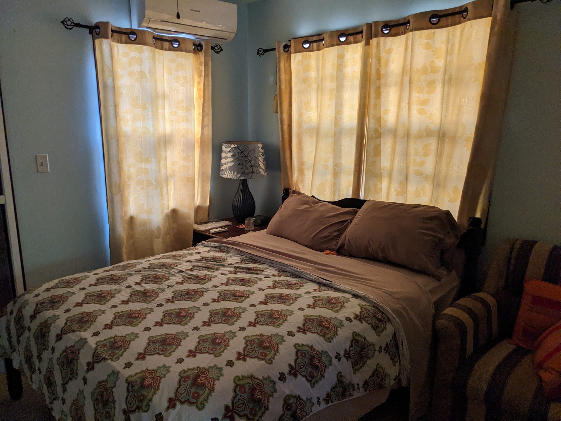 Casita bedroom with queen bed, teal accent wall, and golden curtains
