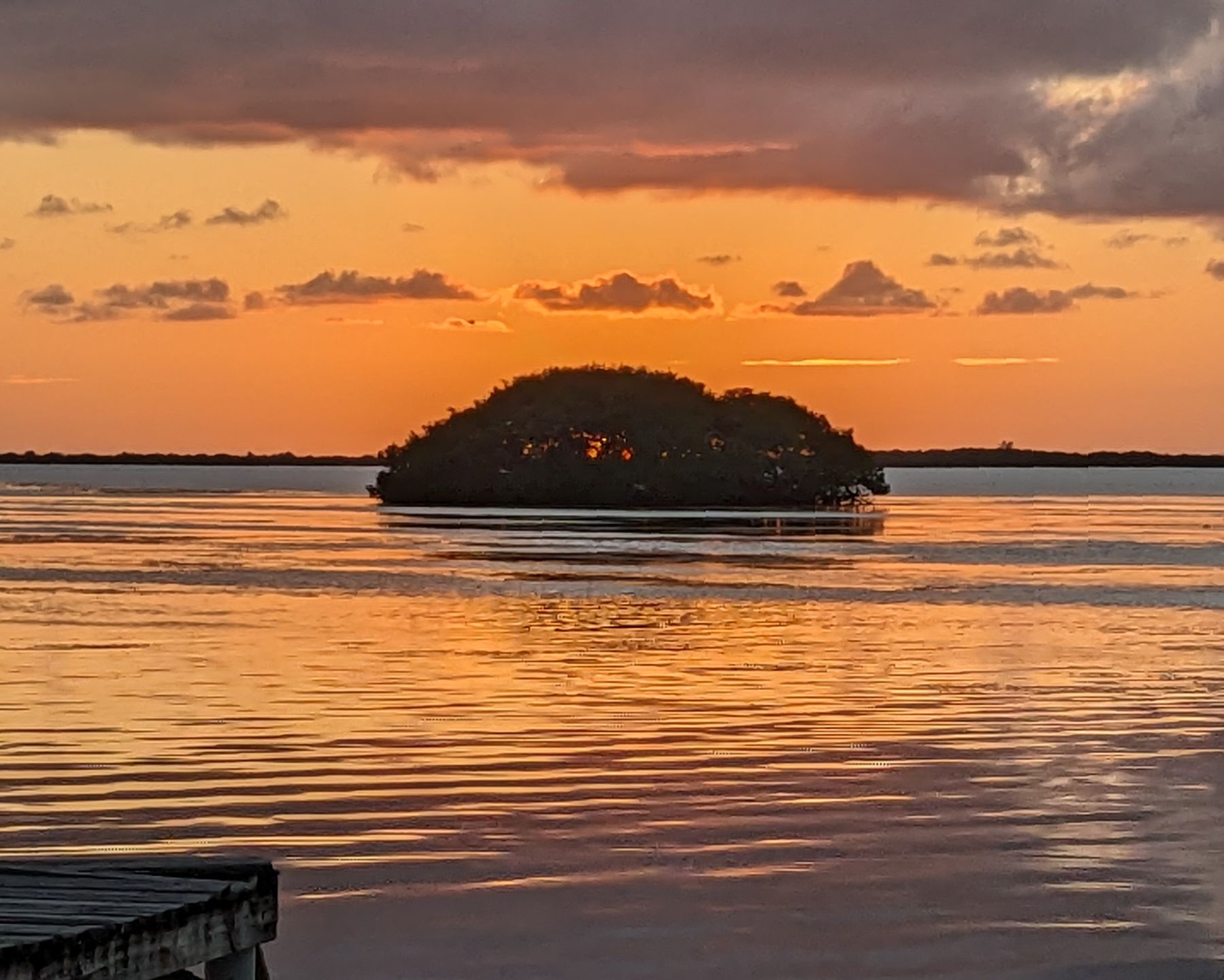 Golden sunset over the Caribbean Sea with island silhouette and dock, Ambergris Caye, Belize